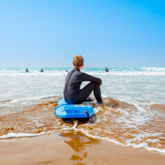 teenager sitting on surf looking ocean