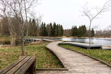 Fototapeta premium A wooden walkway leads to a lake with a lake in the background.