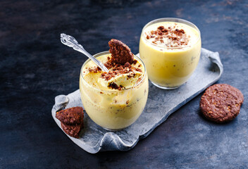Traditionelles Sanddorn Orange Mousse mit Keksen und Streusel serviert als close-up in einem classic Design Glas