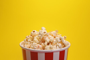Paper cup with popcorn on yellow background. copy space for text