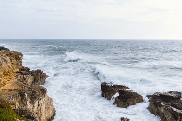 Obraz premium Coastline with atlantic ocean in Cascais, Portugal. Waves at the shore and rocky hills