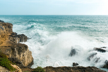 Fototapeta premium Coastline with atlantic ocean in Cascais, Portugal. Waves at the shore and rocky hills