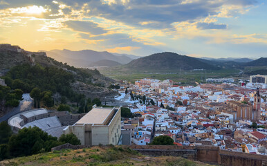 Buildings, houses and streets in city, aerial view. View of rooftops and streets of city of Sagunto in Spain. Town against backdrop of mountains. Roofs of houses and roofs from side of Sagunto Castle.