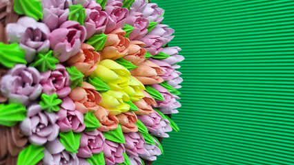 Multicolored cream tulips on a cake on a background of green corrugated paper