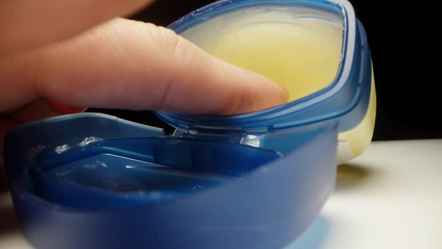 In a blue jar with vaseline, I poke my finger and bring it to the camera. Vaseline on the finger macro.