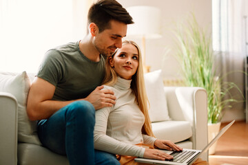 Obraz premium Beautiful young happy couple online via laptop at home