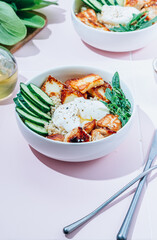 Buddha bowl dish with grilled Halloumi cheese, quinoa, chicken fillet, cucumber, arugula and egg.