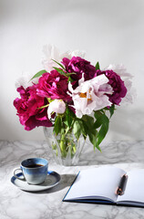 Bouquet of beautiful peonies with cup of coffee
