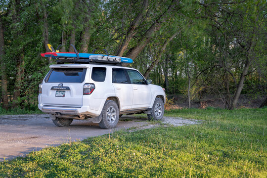 Blackwater, MO, USA - April 21, 2023: Toyota 4Runner SUV with a performance stand up paddleboard (Starboard Waterline) on roof racks at a shore of the Lamine River in spring scenery.