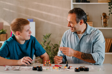 Happy father and his son enjoying together at home while playing with toys.