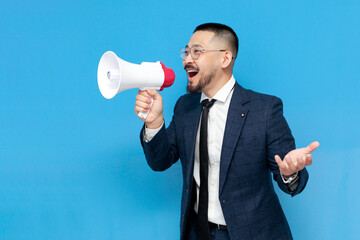 successful asian businessman in suit and glasses announces the news in megaphone on blue isolated...