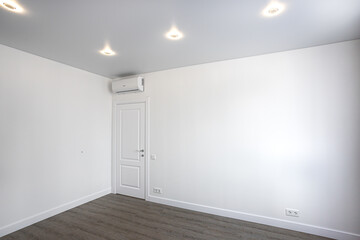 Empty room without furniture with white walls and ceiling, door and air conditioner