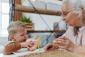 Little boy having snack with his grandmother.