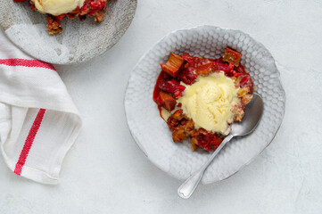 Homemade Rhubarb and Strawberry crumble with rolled oats and vanilla ice cream scoop. Spring healthy dessert.