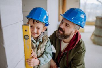 Father and his little son working on their unfinished house.