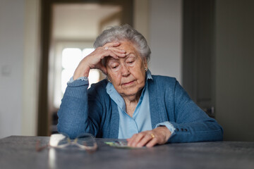 Senior woman counting her money at home. - obrazy, fototapety, plakaty