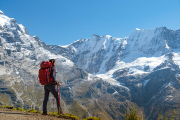 Naklejka premium Sporty woman standing in front of snow mountains and enjoying view of Switzerland nature. Wanderlust, sport, beauty in nature.
