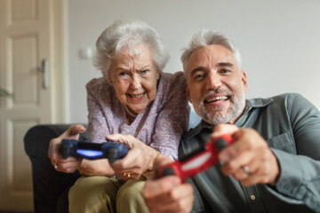 Mature man visiting his senior mother at her apartment, playing video games.