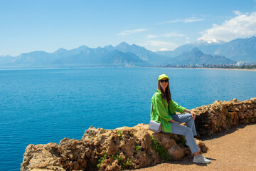 Young woman closeup is sitting on the mountains background. Antalya observation deck in april 2023.