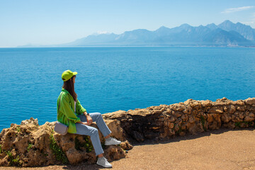 Young woman closeup is sitting on the mountains background. Antalya observation deck in april 2023.