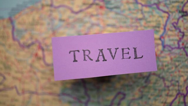 Travel printed on a purple note in front of a map