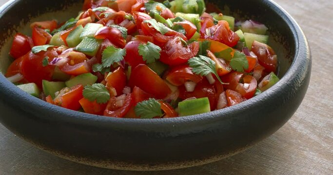 Pico de Gallo salsa in a bowl. Traditional Mexican cuisine dish with tomato, cucumber, onion and fresh coriander. Table spin.