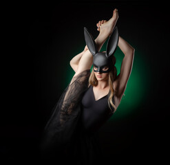 ballerina girl with a raised leg in a rabbit mask on a dark background