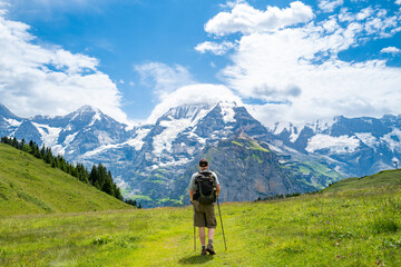 Fototapeta na wymiar Senior man hiking the Mountain view trail from Allmendhubel to Grütschlap in the Jungfrau region of the Swiss Alps, Switzerland. 