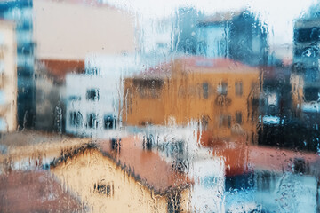 View of city through the window in raindrops during downpour