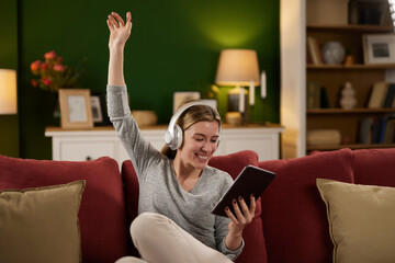 Obraz premium Smiling woman enjoys listening music on digital tablet at home