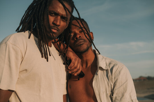 Portrait of two models African men wearing dreadlocks on ocean posing during sunset