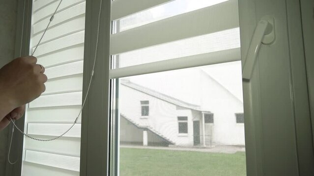 Close-up of men's hands lifting roller blinds on the window in a chain Generative AI