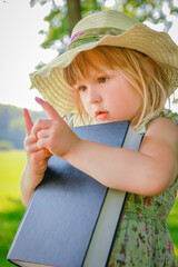 a happy child with a book on the nature of the Bible in the Park