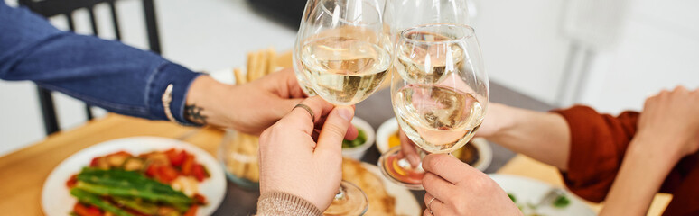 cropped view of gay man clinking wine glasses with boyfriend and parents near supper in kitchen, banner. 
