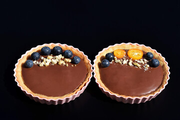 Shortbread tartlets with chocolate pudding, fresh blueberries, kumquat slices and cashew nuts