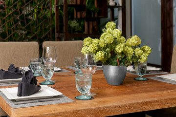 Massive wooden dining table with beautiful flower centerpiece on the balcony