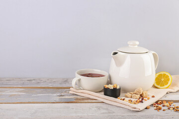 Teapot, cup of tea and dried fruits mix on white wooden table