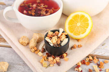 Bowl with dried fruit mix and cup of tea on white wooden table, closeup