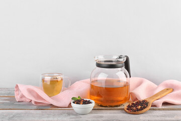 Teapot, glass and bowl with dried fruit tea on white wooden table