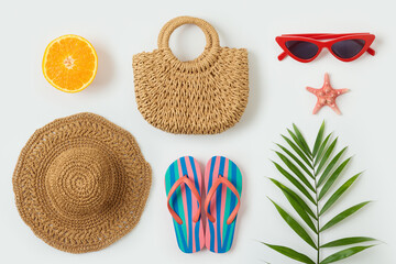 Summer vacation objects. Fashion bag; beach hat, flip flops and palm tree leaf  on white background. Top view from above