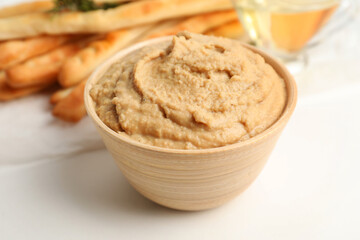Bowl with tasty hummus on light background, closeup