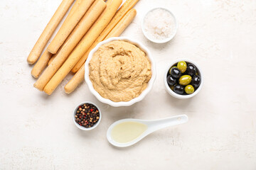 Bowl with tasty hummus and Italian Grissini on light background