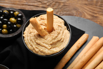 Bowl with tasty hummus and Italian Grissini on wooden background