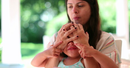 Cute playful mother and little girl child play and interaction together. Daughter and mom playing covering face