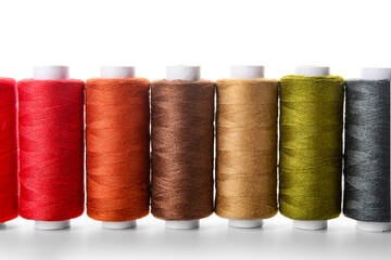 Row of different thread spools on white background, closeup