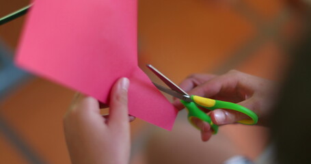 Child hands cutting paper with scissors