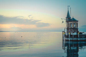 Beautiful sunrise view from Imperia statue to lighthouse at harbor entrance and Lake Constance in...
