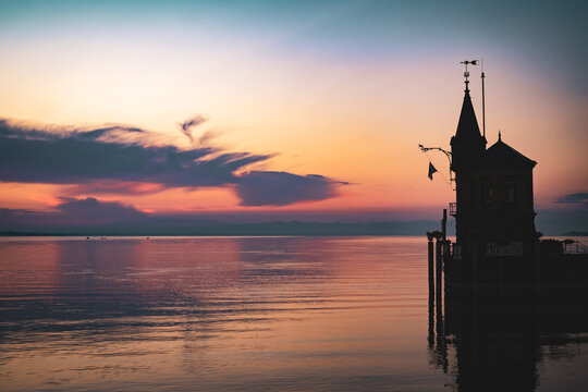 Beautiful sunrise view from Imperia statue to lighthouse at harbor entrance and Lake Constance in early morning hours. Steamer harbor, Constance, Baden-Württemberg, Germany, Europe.