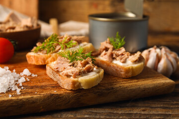 Board with delicious tuna bruschettas on wooden table