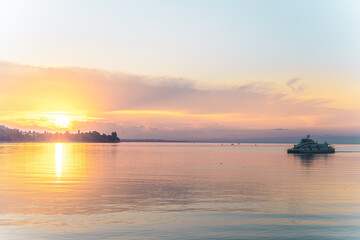 Beautiful sunrise view from Imperia statue at harbor entrance with catamaran ferry on lake...